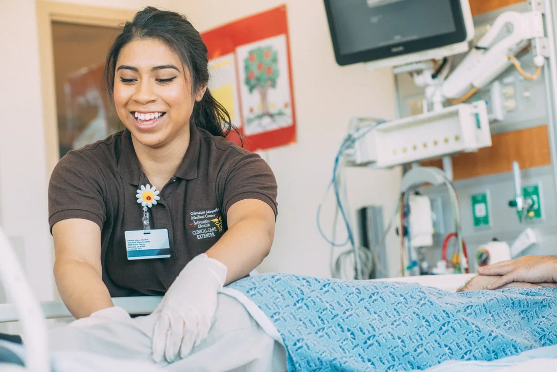 Health Scholar supporting a patient at the bedside in a clinical setting